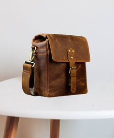 a brown leather bag sitting on top of a white table