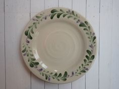 a white plate with green and purple designs on the rim against a wooden wall background