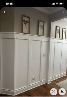 a room with white paneling and pictures on the wall