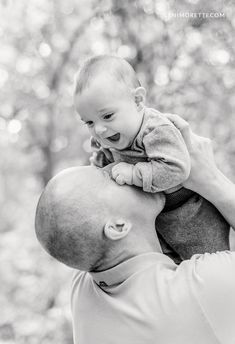 a man holding a baby up to his face while he holds it in the air