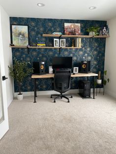 a home office with blue wallpaper and two computer desks