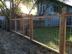 the fence is made of wood and has wire on it, along with some grass