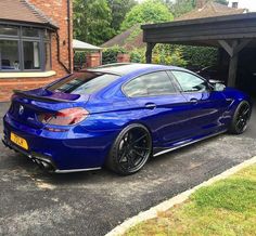 a blue sports car parked in front of a house with its hood up and the door open