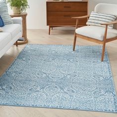 a blue area rug in a living room with two chairs and a dresser behind it