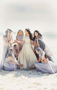 a group of women standing next to each other on top of a sand covered beach