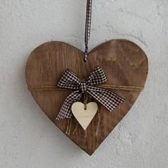 a wooden heart with a bow hanging on a wall