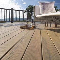 a wooden deck with a chair and pillow on it, along with the ocean in the background