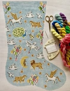 a pair of scissors and some yarn next to a stocking with horses on it