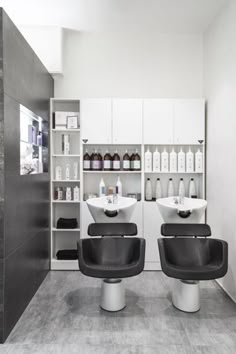 two salon chairs in front of shelves with bottles on them