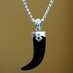 Carved from a single piece of obsidian a dark fang forms the pendant of this men's necklace from Bali. Henry Anthony Sanny designs the necklace which cradles the fang with sterling silver studded with a smaller piece of obsidian. Black Sterling Silver Amulet Necklace, Black Carved Sterling Silver Jewelry, Mens Silver Jewelry, Onyx Necklace, Sterling Silver Mens, Men's Necklace, Garnet Rings, Jewelry Packaging, Sterling Silver Studs