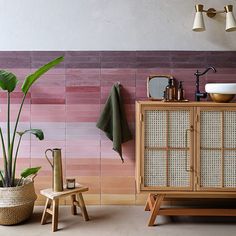 a bathroom with pink and purple tiles on the wall, potted plant next to it