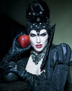 a woman in costume holding an apple up to her face