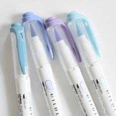 three pens are sitting next to each other on a white surface with blue and purple tips