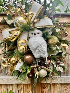 a wreath with an owl and christmas ornaments hanging on the side of a wooden fence