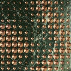 many copper balls are arranged on a green marble surface, forming a pattern in the shape of a spider's web