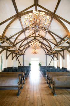 an empty church with wooden pews and chandelier