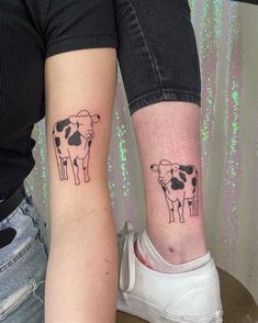 two people with matching tattoos on their arms, one has a cow and the other has a sheep