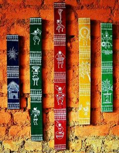 four different colored wooden sticks are hanging on a brick wall with designs painted on them