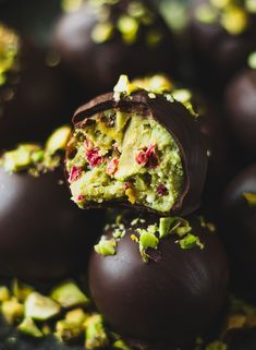 chocolate covered truffles with pistachio toppings on a black plate, ready to be eaten