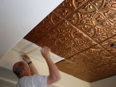 a man is painting the ceiling with gold paint and some brown tinkles on it