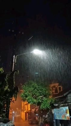 a street light shines brightly in the rain at night with no one around it