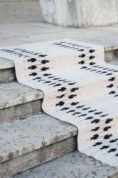 a cat sitting on top of some steps next to a carpeted stair case with black and white designs