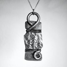 This unique pendant captures the essence of nature through hand-forged iron and intricate engravings of towering trees. Skillfully crafted by a blacksmith, this piece combines rustic charm with timeless artistry, making it a perfect gift for nature lovers or anyone seeking a piece that resonates with the outdoors. The pendant's organic texture and forest scene evoke a deep connection to wilderness and craftsmanship, serving as a reminder of resilience and beauty in simplicity. Made with care and dedication, this necklace is an accessory and a statement of artistry and tradition. -It measures approximately 55 mm high -Comes with a stainless steel chain in the length of your choice (Note: Since it's all handmade sizes and shapes may slightly vary) Iron Necklace, Beauty In Simplicity, Hand Forged Iron, Deep Connection, Forged Iron, Forest Landscape, Unique Pendant, Gifts For Nature Lovers, Blacksmithing