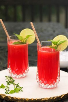 two glasses filled with watermelon juice and garnished with limes on top