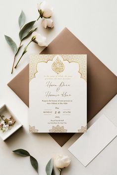 the wedding stationery is laid out on top of an envelope with flowers and greenery