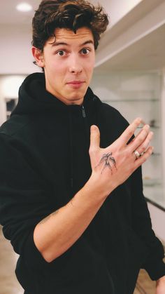 a young man making the vulcan sign with his hand while wearing a black hoodie