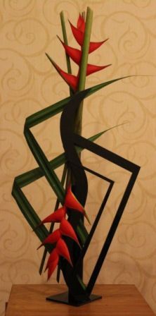 a vase with red and green flowers in it on a wooden table next to a wall