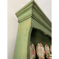 an old green china cabinet with plates on it