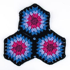 two crocheted hexagons are shown on a white surface with pink and blue flowers