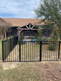 a black gate in front of a house with a car parked on the other side