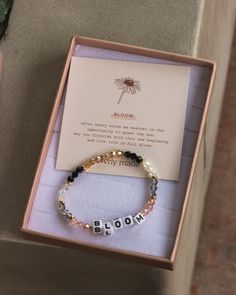 a bracelet with the word mom written on it in a box next to a note