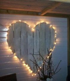 a white heart shaped mirror with lights on the wall next to a potted plant