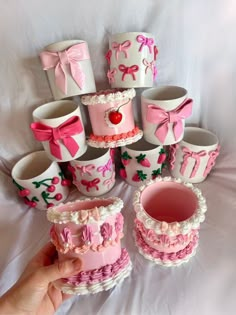 there are many pink and white cupcakes in the shape of cakes with bows on them