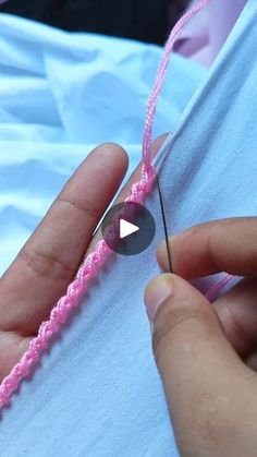 someone is stitching the end of a pink thread