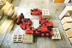 a large letter made out of red and black blocks on pallets in a warehouse