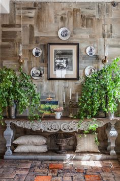 a table with plants and pictures on the wall above it, along with other decorative items