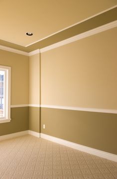 an empty room with a window, carpet and wall paint in the corner is shown