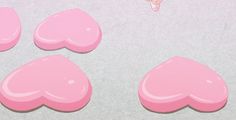 three pink hearts are shown on a white surface with a butterfly flying over them and the bottom half has been cut out