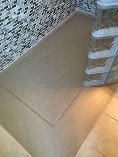 a bathroom with a tile floor and shower stall next to the toilet paper dispenser