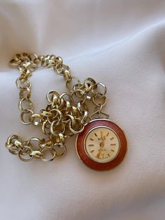 Elegant 1960's Vintage Art Deco Swiss women's Pendant Watch Wilson golden color case inlaid with apricot color enamel with clear white color dial. Very elegant classic present for women for every occasion. Collectible Swiss pendant ladies watch with new stainless steel necklace in golden color. An accent that would make every woman look stunning. Amazing present for vintage watch lovers. Very elegant classical gift for ladies. Pre-owned. The item has been used previously. It may have some signs of cosmetic wear but is fully operational and functions as intended. Checked and serviced. Exceptional gift for the loved one. The watch is in excellent condition and has no visible defects (please, see the pictures). Watch runs properly when tested. Should be wound up regularly on every 24 hours. T Retro Round Watch As Gift, Retro Round Watch For Gift, Vintage Pocket Watch Gift, Retro Gold-tone Jewelry For Gift, Retro Gold-tone Jewelry Gift, Vintage Yellow Gold Watches As Gifts, Retro Yellow Gold Watch As Gift, Retro Yellow Gold Watch For Gift, Vintage Jewelry And Watches With Round Dial For Gift