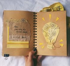 a hand holding a notebook open to a page with an image of a light bulb on it