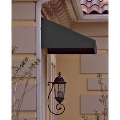 an old fashioned street light hanging from the side of a building with a green awning over it