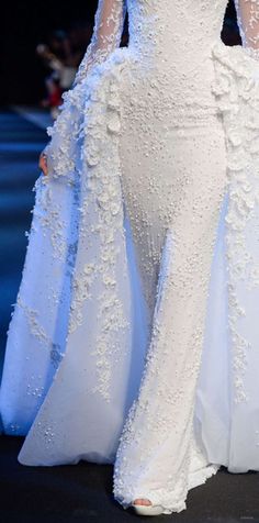 a woman in a white dress on a runway