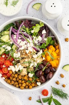 a white bowl filled with vegetables and chickpeas on top of a marble table