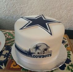 there is a white cake with a blue star on top and a football helmet on the bottom