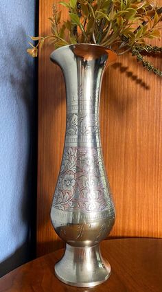 a silver vase filled with flowers on top of a wooden table